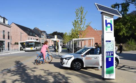 Vrouw op deelfiets en vrouw met deelwagen aan het Hoppin punt in Kasterlee