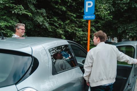 Twee mannen stappen in een deelauto.