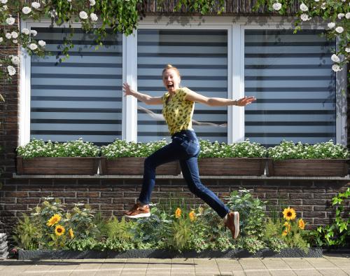 Vrouw springt in de lucht voor geveltuin