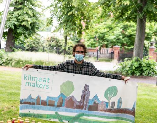 Een Klimaatmaker houdt een spandoek vast over het project Klimaatmakers.