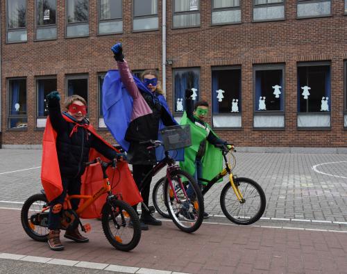 3 kinderen op hun fiets met superhelden cape